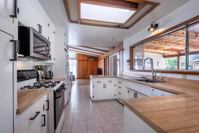 kitchen with vaulted ceiling with beams, kitchen peninsula, sink, white cabinetry, and appliances with stainless steel finishes