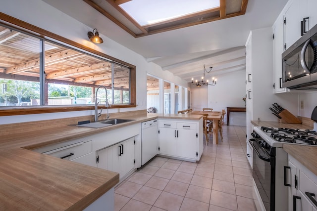 kitchen with gas range oven, white cabinetry, sink, and kitchen peninsula