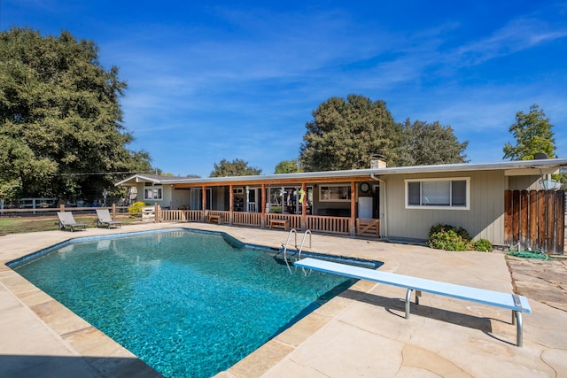 view of swimming pool featuring a diving board and a patio area