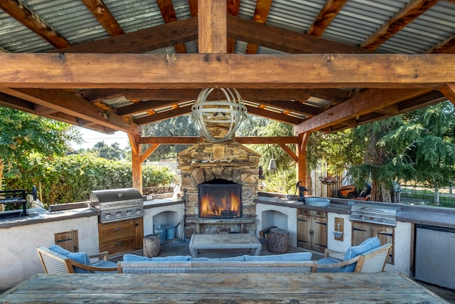 view of patio with a gazebo, an outdoor stone fireplace, and area for grilling