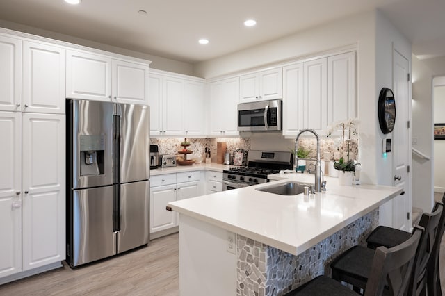 kitchen featuring white cabinets, a breakfast bar area, light hardwood / wood-style flooring, sink, and stainless steel appliances