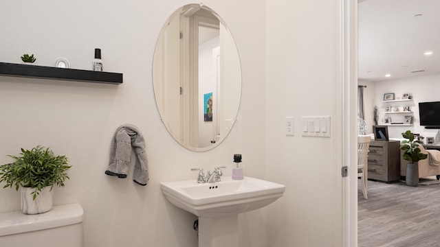 bathroom featuring toilet, wood-type flooring, and sink