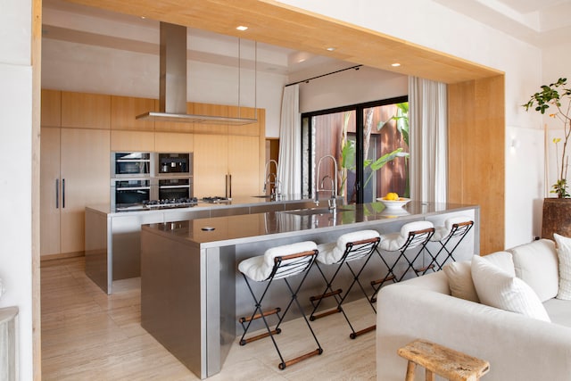 kitchen with light hardwood / wood-style floors, a kitchen island with sink, and a kitchen bar