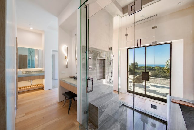 bathroom with an enclosed shower, wood-type flooring, and a high ceiling