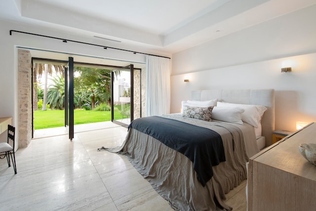 bedroom featuring access to exterior and a tray ceiling