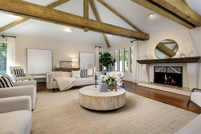 living room featuring vaulted ceiling with beams, a large fireplace, and wood-type flooring