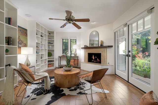 living area with french doors, ceiling fan, and light hardwood / wood-style flooring