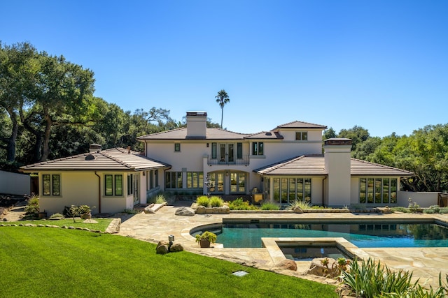 rear view of property with a yard, a patio area, and a swimming pool with hot tub