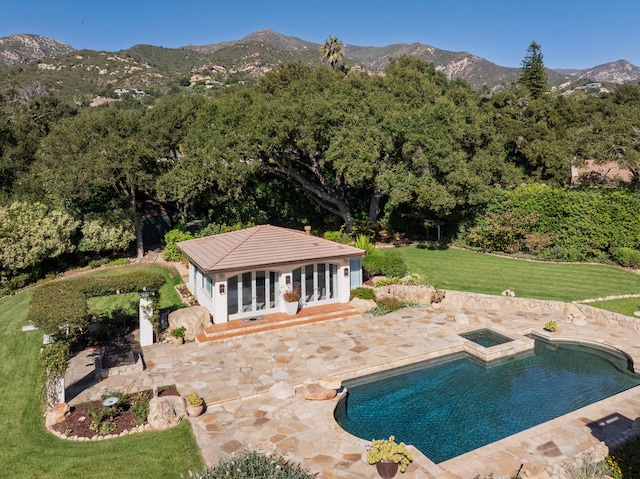 view of swimming pool with an outdoor structure, a mountain view, a patio, and a lawn