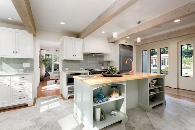 kitchen featuring a center island with sink, beam ceiling, light hardwood / wood-style floors, and plenty of natural light