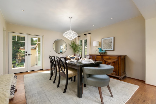 dining area with french doors, light hardwood / wood-style floors, a notable chandelier, and a healthy amount of sunlight