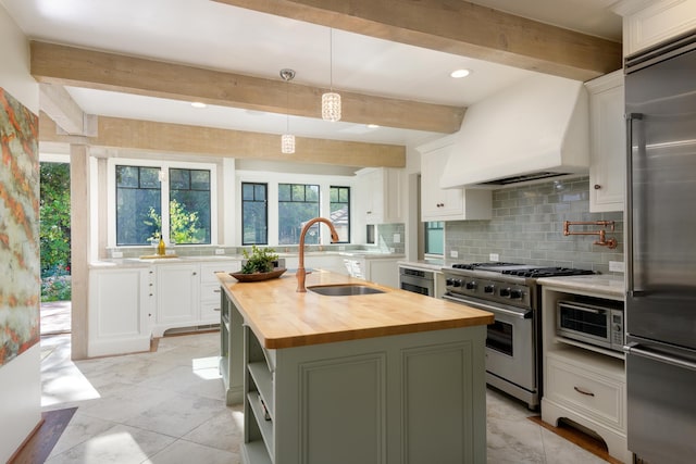 kitchen with a center island with sink, hanging light fixtures, wood counters, beamed ceiling, and high quality appliances