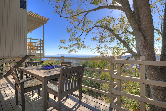 wooden terrace featuring outdoor dining space and a water view