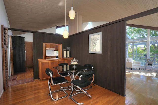 dining area featuring wooden ceiling, wood finished floors, and wooden walls