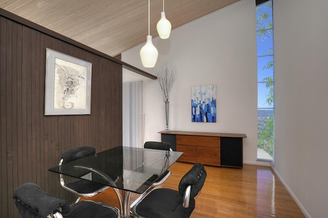 dining space featuring baseboards, wood ceiling, light wood-style flooring, and wooden walls