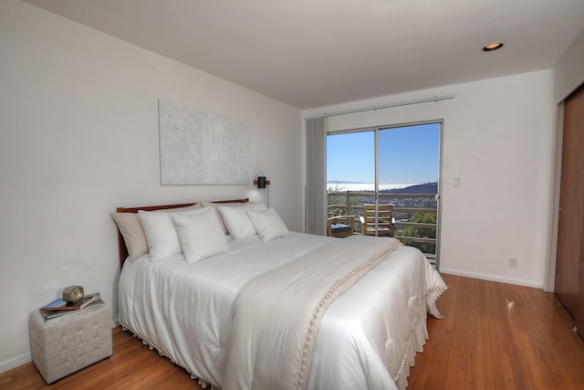 bedroom featuring access to exterior, baseboards, and wood finished floors