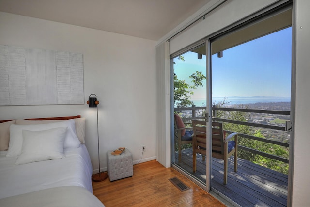 bedroom with wood finished floors, visible vents, and baseboards