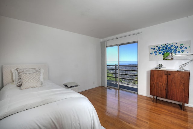 bedroom featuring access to outside, baseboards, and wood finished floors