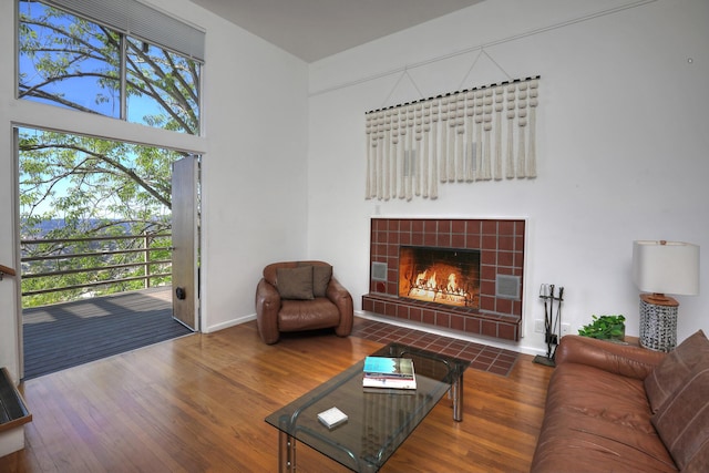 living area with baseboards, a tiled fireplace, and wood finished floors