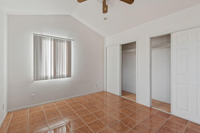 unfurnished bedroom featuring ceiling fan, lofted ceiling, tile patterned flooring, and two closets