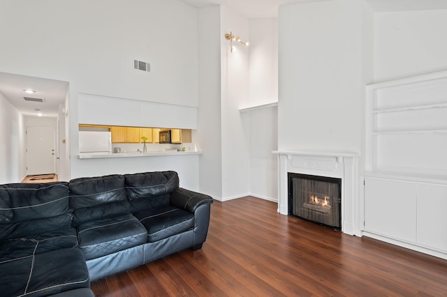 living room featuring a high ceiling and dark hardwood / wood-style floors