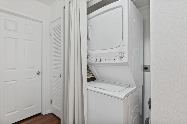 washroom featuring stacked washer and dryer and dark hardwood / wood-style flooring