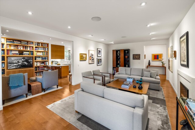 living room featuring recessed lighting, a glass covered fireplace, and wood finished floors