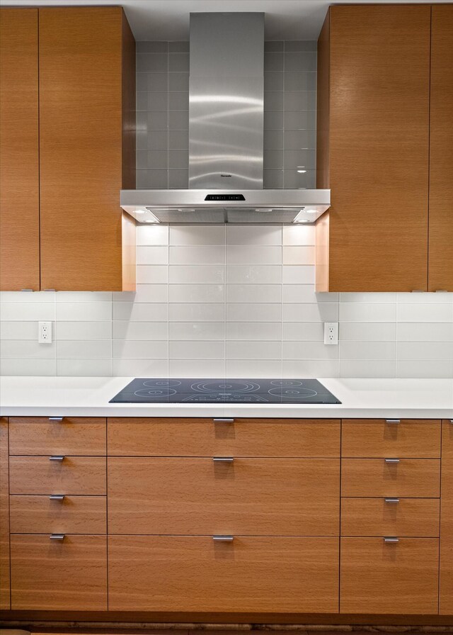 kitchen featuring wall chimney range hood, backsplash, and black electric stovetop