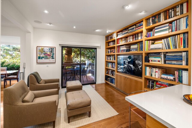 sitting room with built in shelves, a wealth of natural light, recessed lighting, and wood finished floors