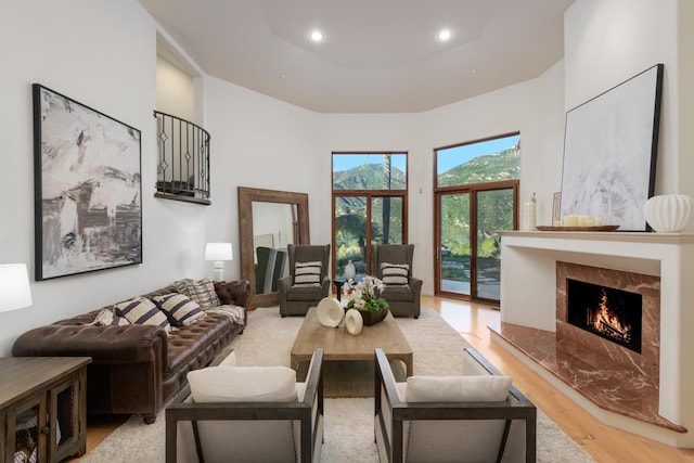 living room featuring a premium fireplace, a high ceiling, and light wood-type flooring