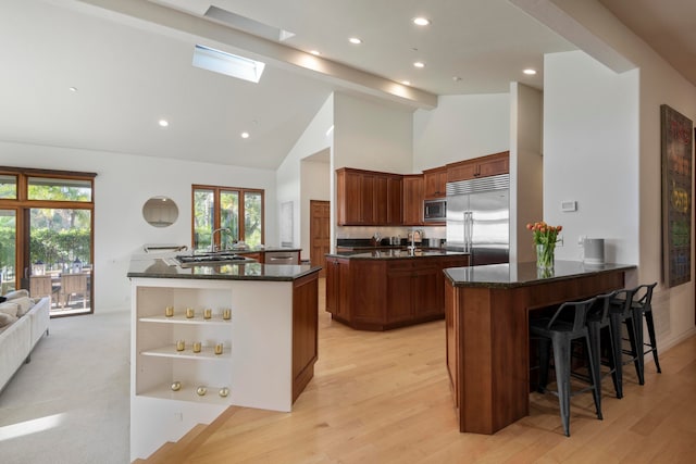 kitchen featuring built in appliances, light hardwood / wood-style floors, high vaulted ceiling, and kitchen peninsula