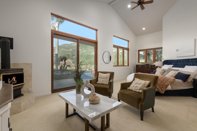 bedroom featuring a wood stove, access to exterior, ceiling fan, high vaulted ceiling, and light colored carpet