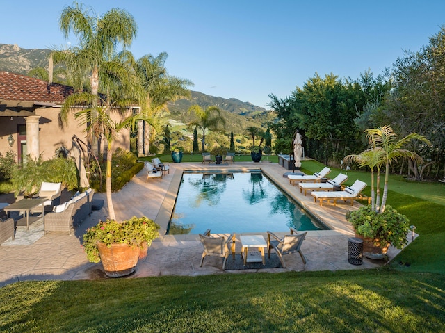 view of swimming pool featuring a patio area, a lawn, and a mountain view