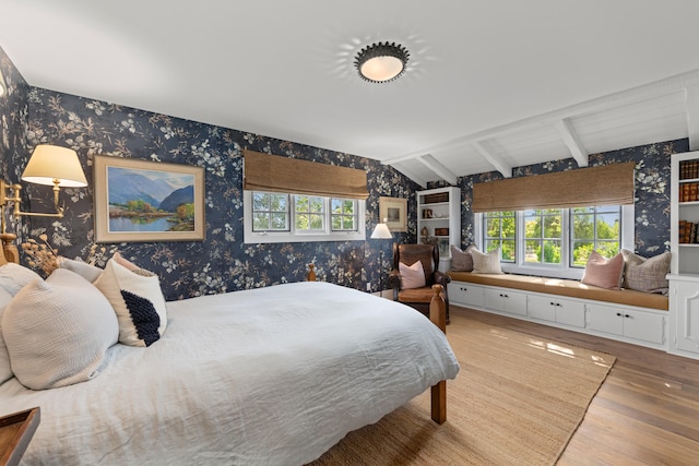 bedroom featuring lofted ceiling with beams, multiple windows, and hardwood / wood-style flooring