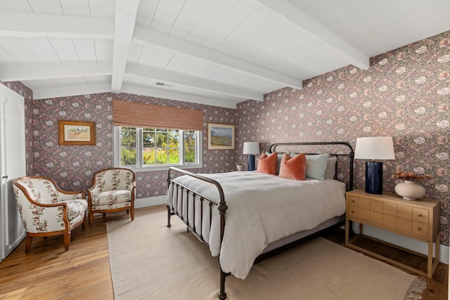 bedroom with vaulted ceiling with beams and light hardwood / wood-style floors