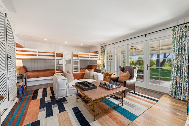 living room with french doors, hardwood / wood-style flooring, and wooden walls