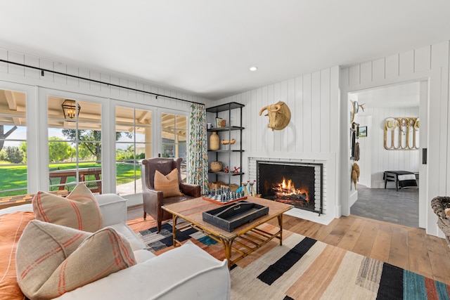 living room featuring wood walls, light hardwood / wood-style flooring, and a fireplace