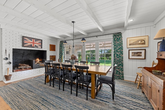 dining space with wood ceiling, beam ceiling, wood-type flooring, and a brick fireplace