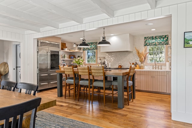 dining area featuring beamed ceiling, light hardwood / wood-style flooring, and sink