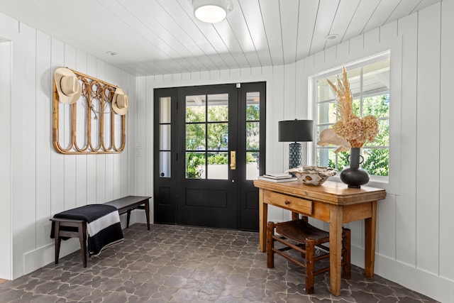 doorway to outside with wood ceiling, a healthy amount of sunlight, and wood walls