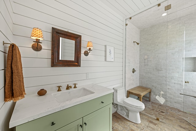 bathroom featuring vanity, toilet, wood walls, and a shower with door