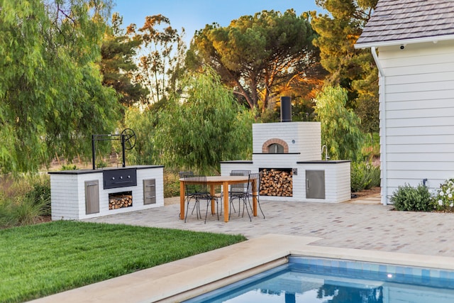 exterior space featuring an outdoor kitchen, a patio area, and a lawn