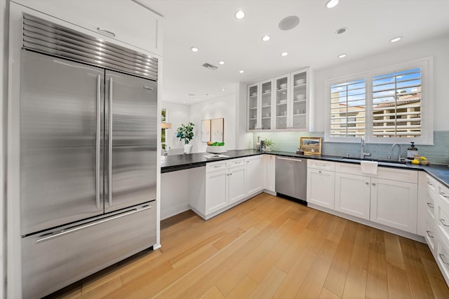71 Seaview Dr, Santa Barbara, CA 93108 - kitchen with stainless steel appliances, dark countertops, glass insert cabinets, decorative backsplash, and white cabinetry