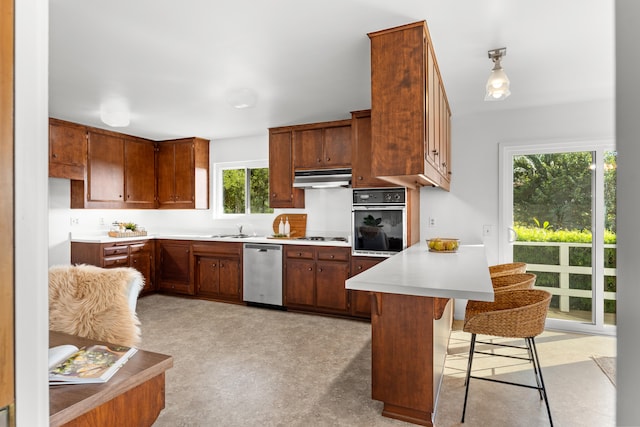 kitchen featuring stainless steel dishwasher, oven, plenty of natural light, and a breakfast bar area