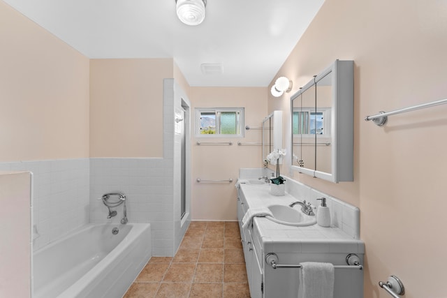 bathroom with a tub to relax in, vanity, and tile patterned floors