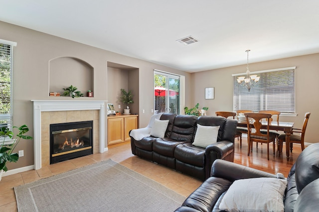 living room featuring an inviting chandelier, light tile patterned floors, and a fireplace