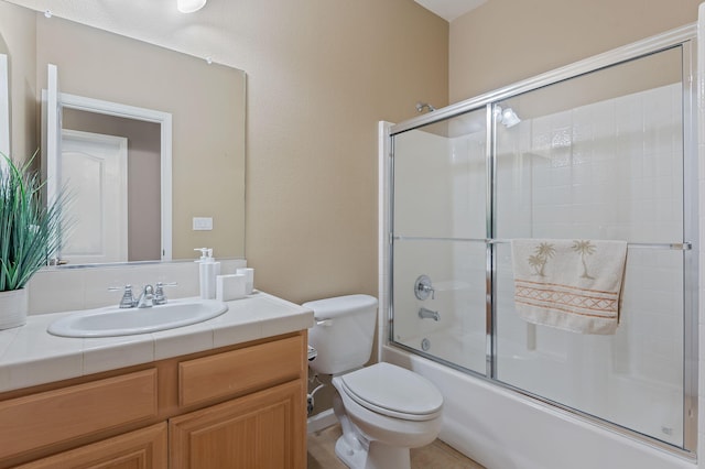 full bathroom with combined bath / shower with glass door, vanity, and toilet