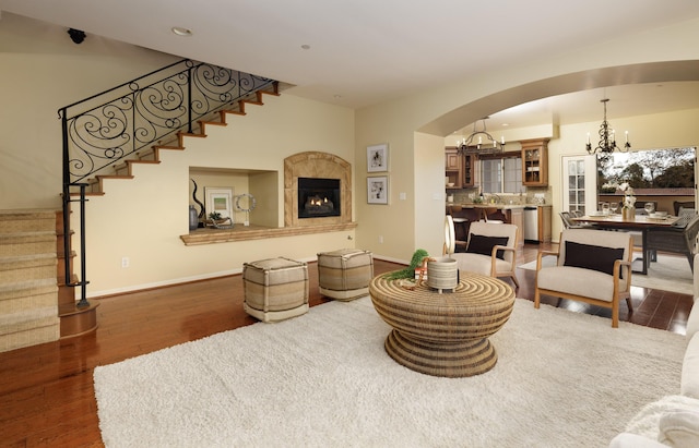 living room featuring an inviting chandelier, dark wood-type flooring, and a tiled fireplace