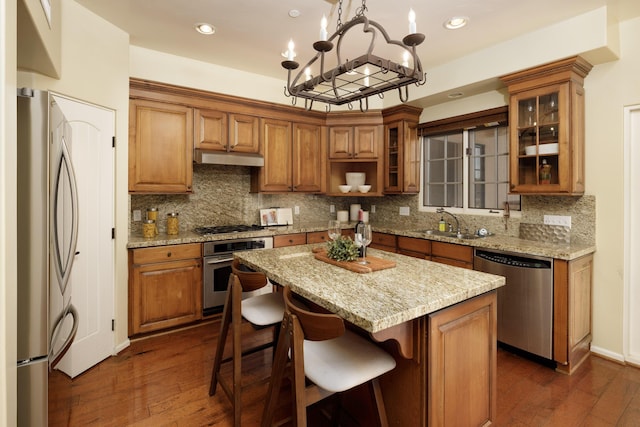 kitchen with dark hardwood / wood-style flooring, stainless steel appliances, a notable chandelier, a center island, and hanging light fixtures