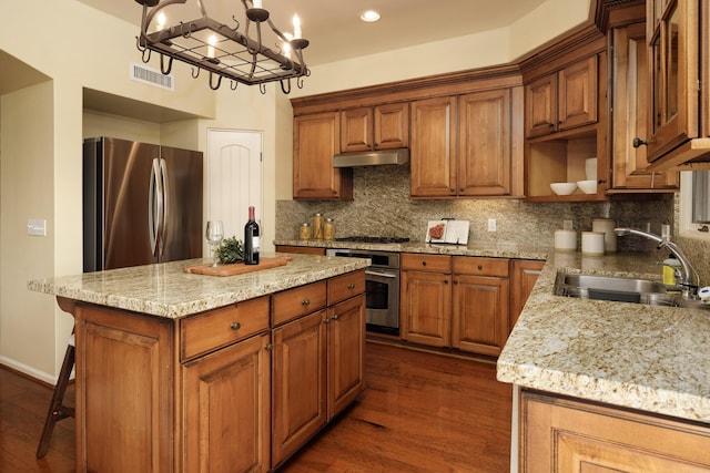 kitchen featuring light stone countertops, sink, a center island, stainless steel appliances, and dark hardwood / wood-style flooring